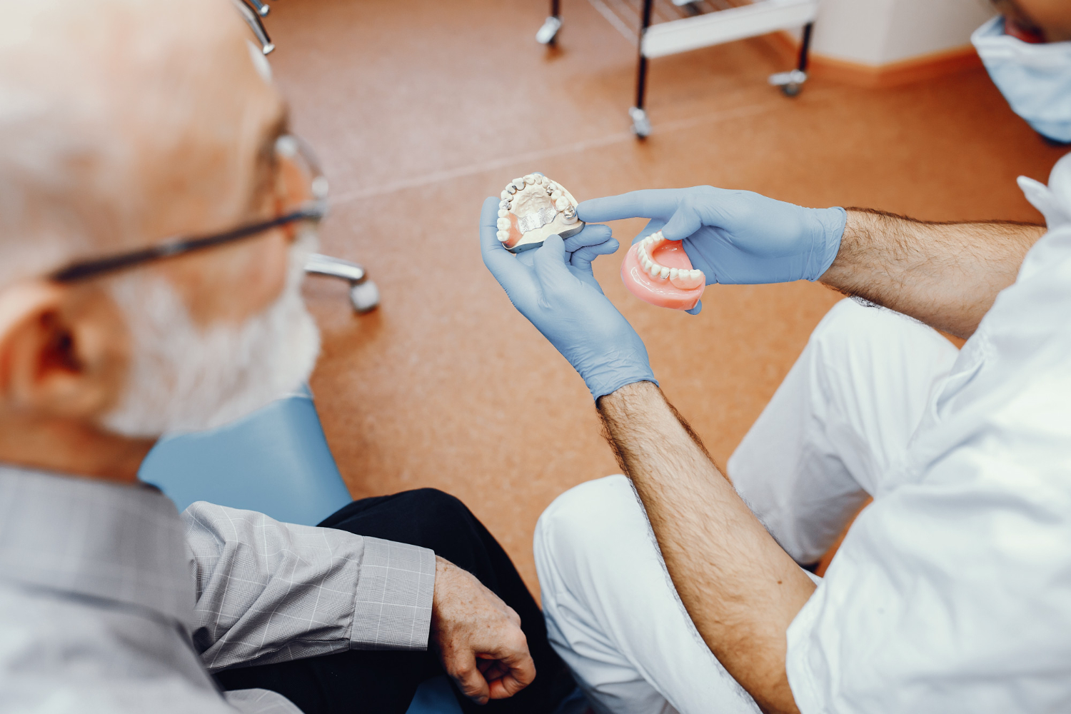 Dentiste présentant différents modèles de prothèses dentaires à un patient lors d'une consultation chez Chadi Dental Clinic à Casablanca.