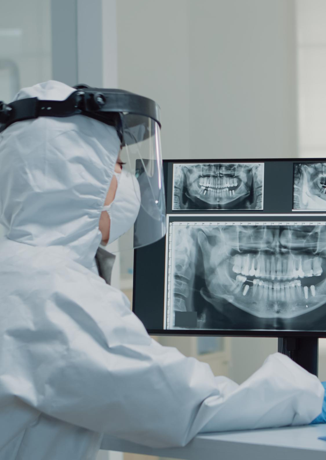 Spécialiste en équipement de protection analysant des radiographies dentaires numériques sur écran dans une clinique dentaire à Casablanca – Chadi Dental Clinic